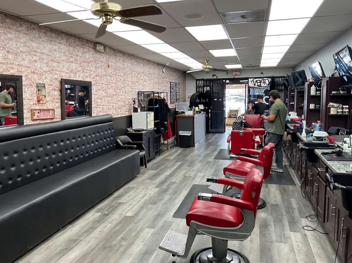 Dapper Cuts Barbershop floor with brick wall, leather waiting bench and barbers at work